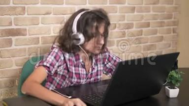 <strong>酷酷</strong>的少年男孩，一头卷曲的<strong>黑</strong>发，穿着格子衬衫，戴着耳机，跳舞，坐在笔记本电脑前